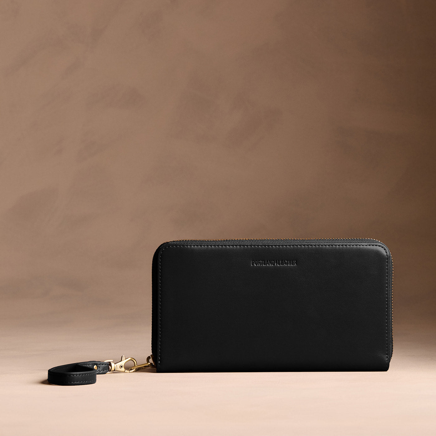 Onyx | Full zip around wallet with a strap on a brown background