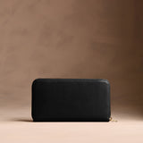 Onyx | Full zip around wallet with a strap on a brown background