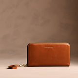 Vintage Tan | Full zip around wallet with a strap on a brown background