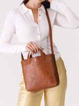 Model wearing a Meadow Mini Crossbody with a white shirt and yellow pants