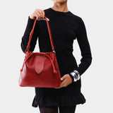 Chili Red Large | Model holding symmetrical leather bag with leather drawstring closure and adjustable shoulder strap