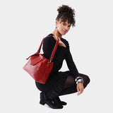 Chili Red Large | Model holding symmetrical leather bag with leather drawstring closure and adjustable shoulder strap