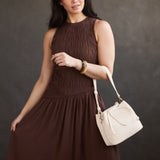 Pebbled Bone Small | Model holding symmetrical leather bag with leather drawstring closure and adjustable shoulder strap