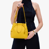 Canary Small | Model holding symmetrical leather bag with leather drawstring closure and adjustable shoulder strap