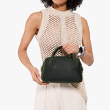 Evergreen Large | A large bowler styled bag with a crossbody strap being held by a model in a neutral outfit