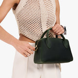 Evergreen Large | A large bowler styled bag with a crossbody strap being held by a model in a neutral outfit