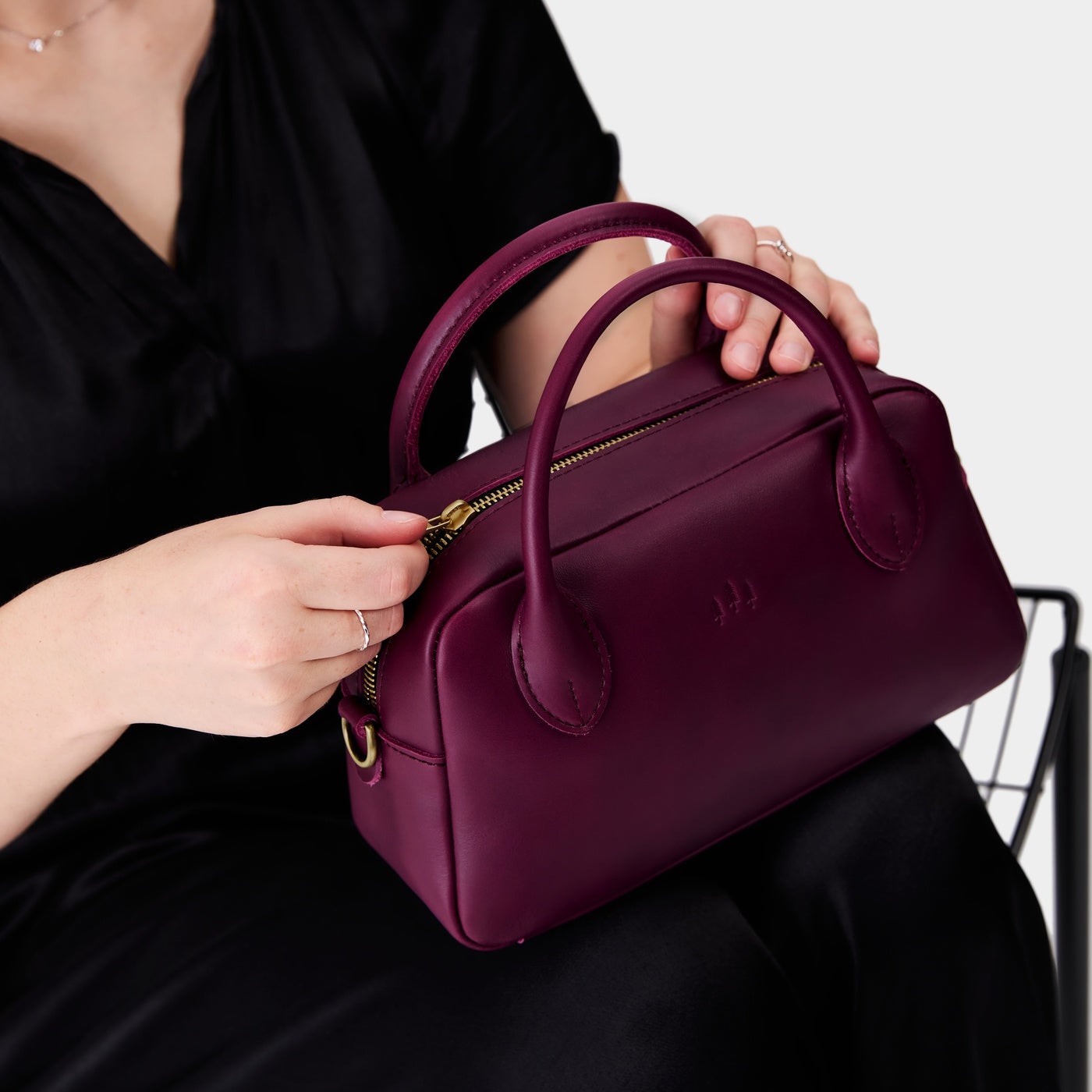Lollipop*Large | A large bowler styled bag with a crossbody strap being held by a model wearing a black dress