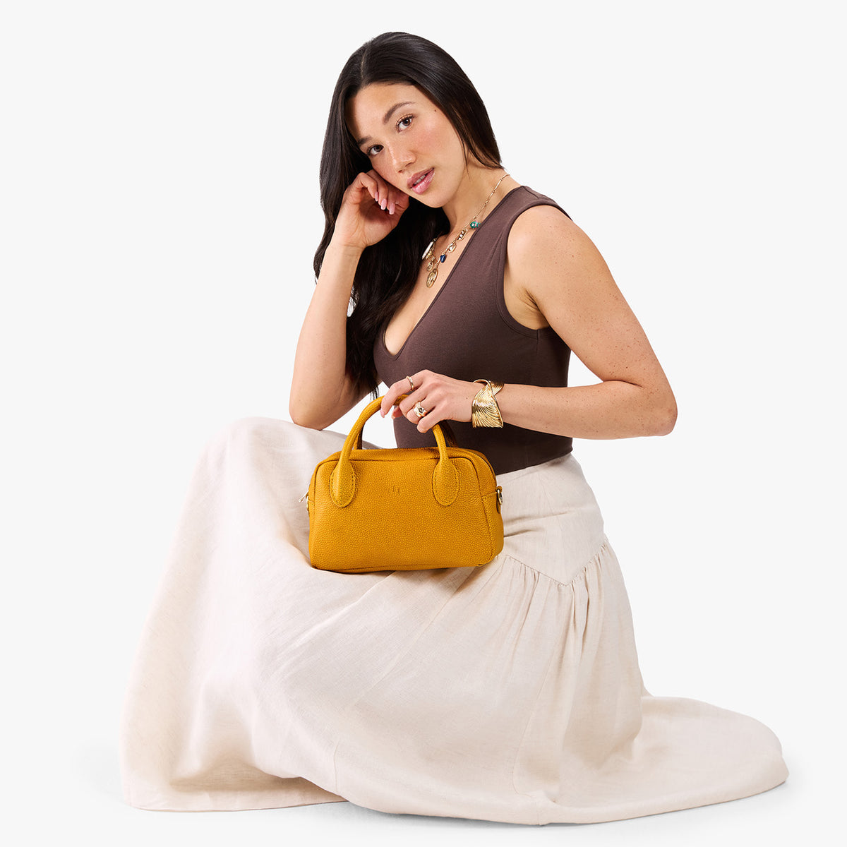 Sunshine*Large | A large bowler styled bag with a crossbody strap being held by a model in a neutral outfit