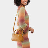 Mango Small | A bowler styled bag with a crossbody strap being worn by a model wearing a multi-colored dress