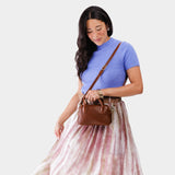Nutmeg Small | A Bowler style purse with a crossbody strap being worn by a model