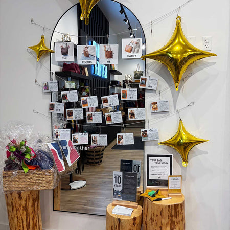 A retail store interior with a large arched mirror on the wall, decorated with gold star balloons and many small printed cards hanging across the mirror