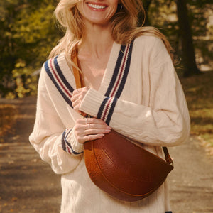 A model outdoors carrying a crescent-shaped leather shoulder bag.