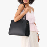 Black Large | Model carrying leather tote bag with handles, adjustable crossbody strap, and two back pockets