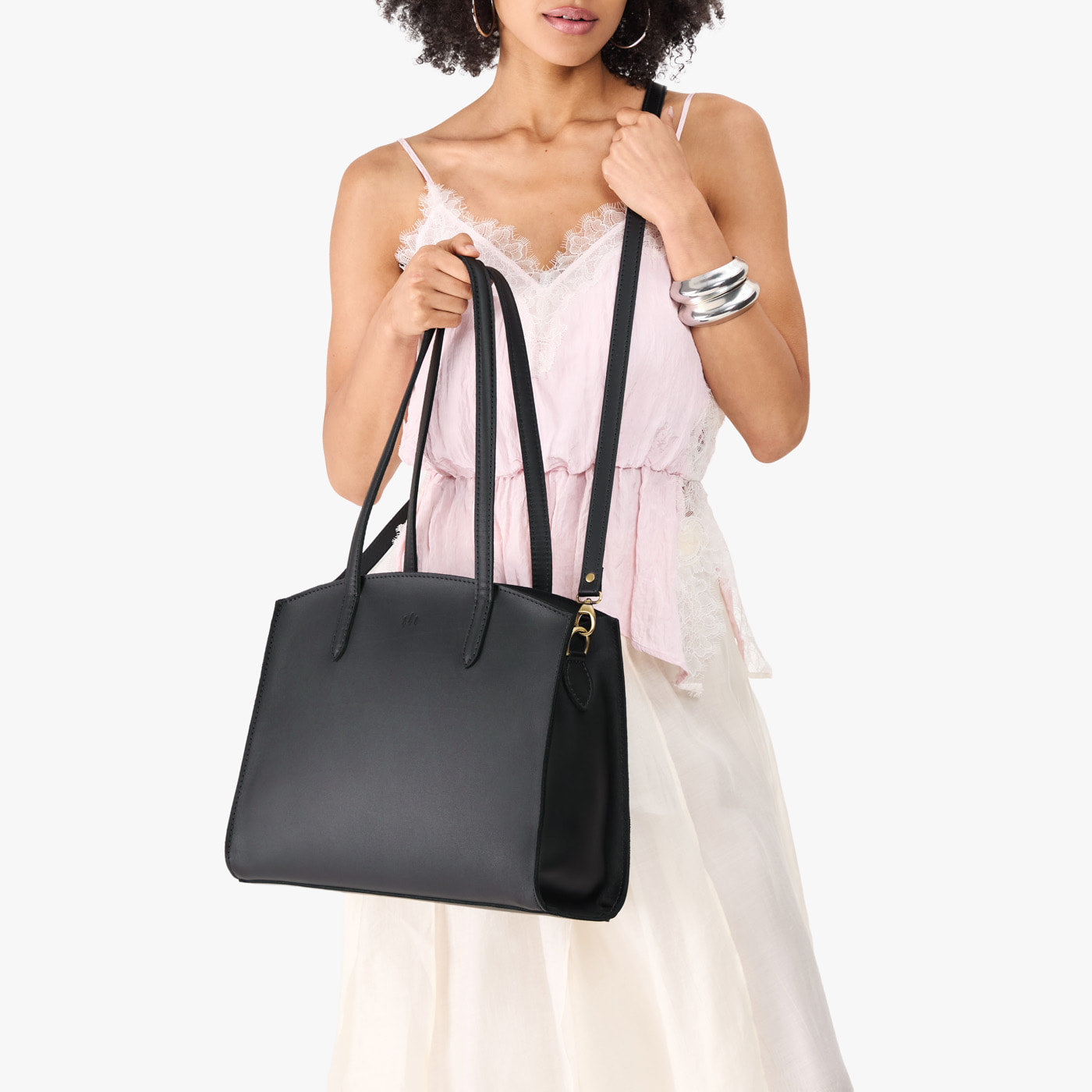 Black*Large | Model carrying leather tote bag with handles, adjustable crossbody strap, and two back pockets