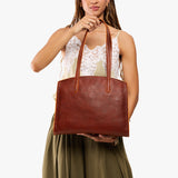 Nutmeg Large | Model carrying leather tote bag with handles, adjustable crossbody strap, and two back pockets