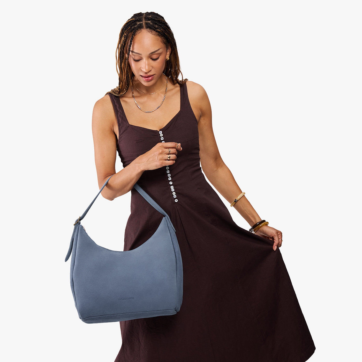Denim*Large | Model holding u-shaped, flat-bottomed leather shoulder bag with adjustable strap