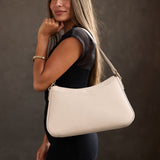 Bone Large | Model holding a bean shaped shoulder bag with a zipper closure