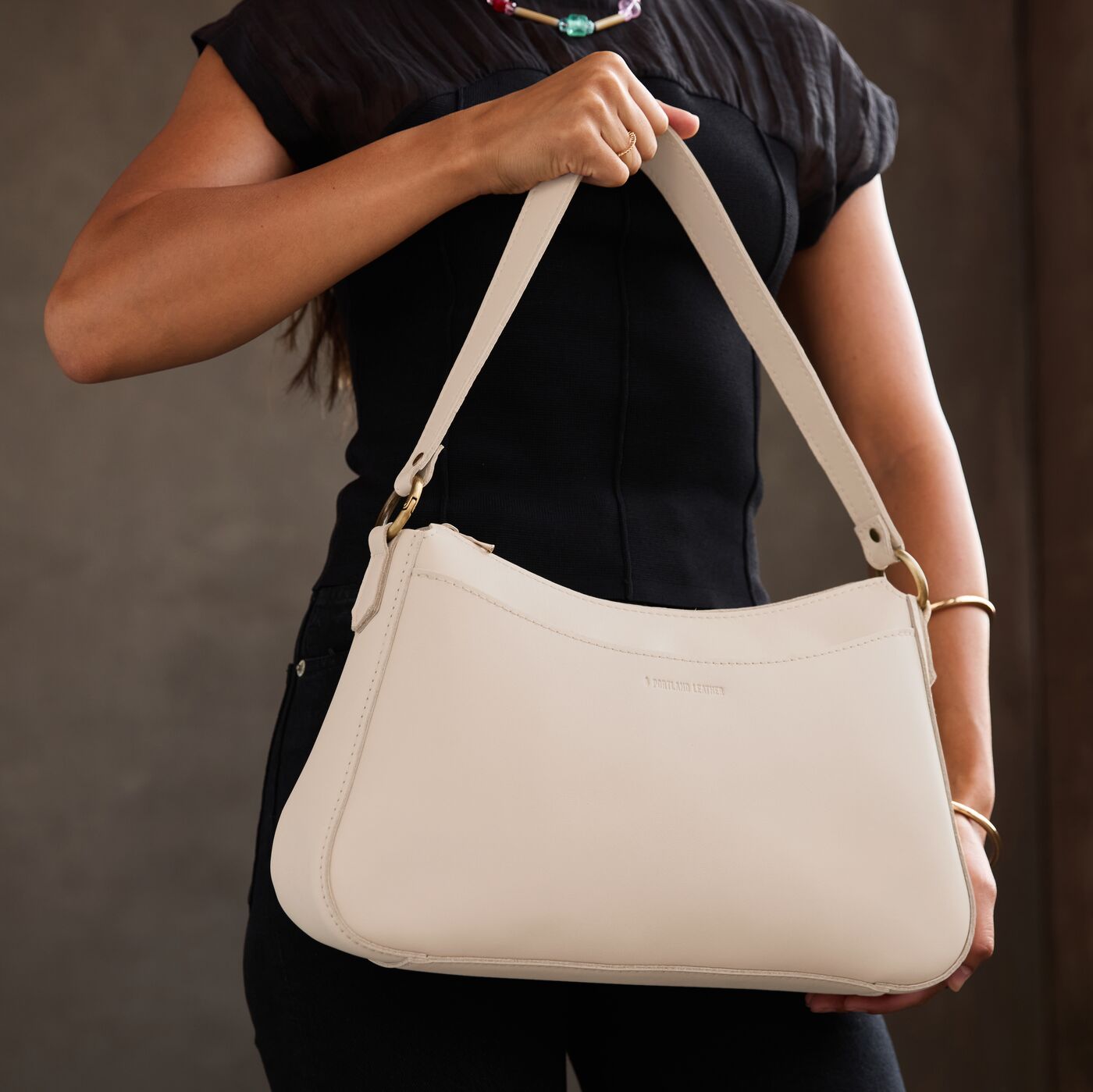 Bone*Large | Model holding a bean shaped shoulder bag with a zipper closure