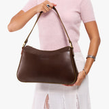 Chocolate Brown Large | Model holding a bean shaped shoulder bag with a zipper closure