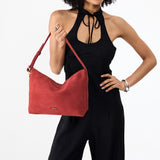 Cinnabar Large | Model holding a Slouchy Shoulder Bag that has a zipper opening and three metal tree emblems