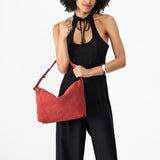 Cinnabar Large | Model holding a Slouchy Shoulder Bag that has a zipper opening and three metal tree emblems