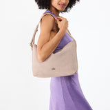 Taupe Large | Model holding a Slouchy Shoulder Bag that has a zipper opening and three metal tree emblems