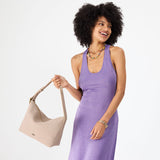 Taupe Large | Model holding a Slouchy Shoulder Bag that has a zipper opening and three metal tree emblems