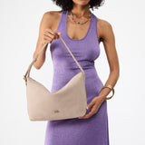 Taupe Large | Model holding a Slouchy Shoulder Bag that has a zipper opening and three metal tree emblems