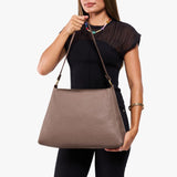 Sparrow Large | Model holding a triangular shoulder bag with antiqued brass finished 