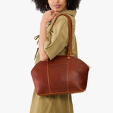 Nutmeg Large | Model holding a half circle crossbody bag with handles and removable crossbody strap 