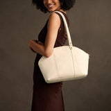 Pebbled Bone Large | Model holding a half circle crossbody bag with handles and removable crossbody strap