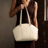 Pebbled Bone Large | Model holding a half circle crossbody bag with handles and removable crossbody strap