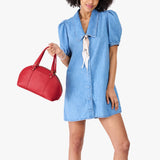 Cherry Small | Model holding a half circle crossbody bag with handles and removable crossbody strap 