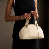 Pebbled Bone Small | Model holding a half circle crossbody bag with handles and removable crossbody strap