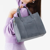 Storm | Model holding structured mid-size tote bag with overlapping panels and crossbody strap
