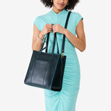 Boreal North/South | Model holding structured wide tote bag with overlapping panels and crossbody strap