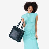 Boreal North/South | Model holding structured wide tote bag with overlapping panels and crossbody strap