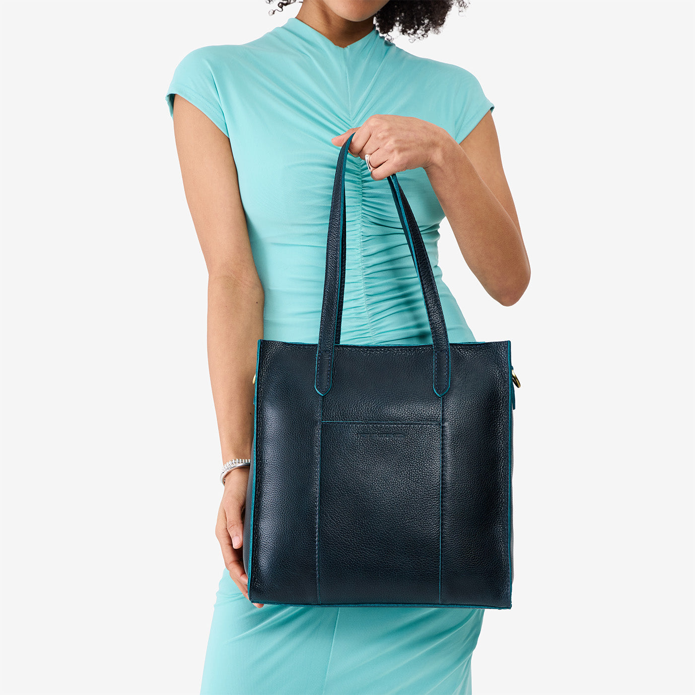 Boreal*North/South | Model holding structured wide tote bag with overlapping panels and crossbody strap