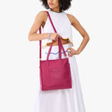 Cosmo North/South | Model holding structured wide tote bag with overlapping panels and crossbody strap