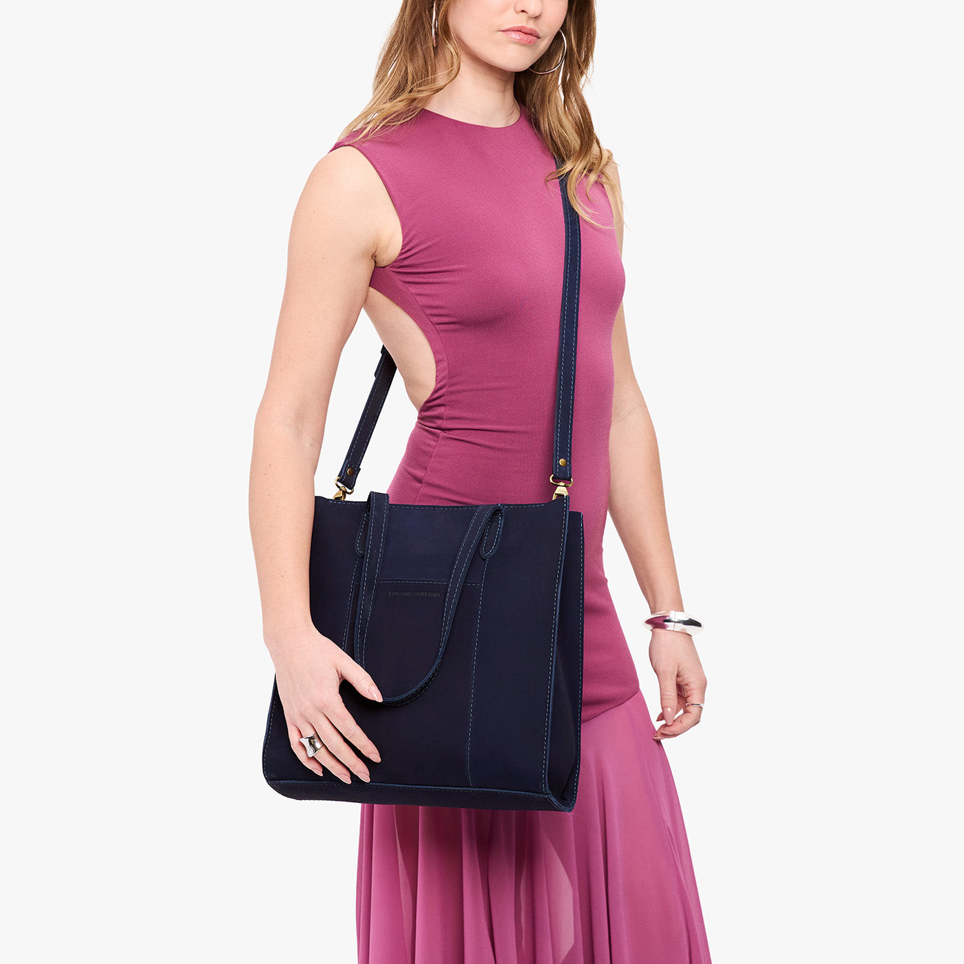 Velvet Blue*North/South | Model holding structured large tote bag with overlapping panels and crossbody strap