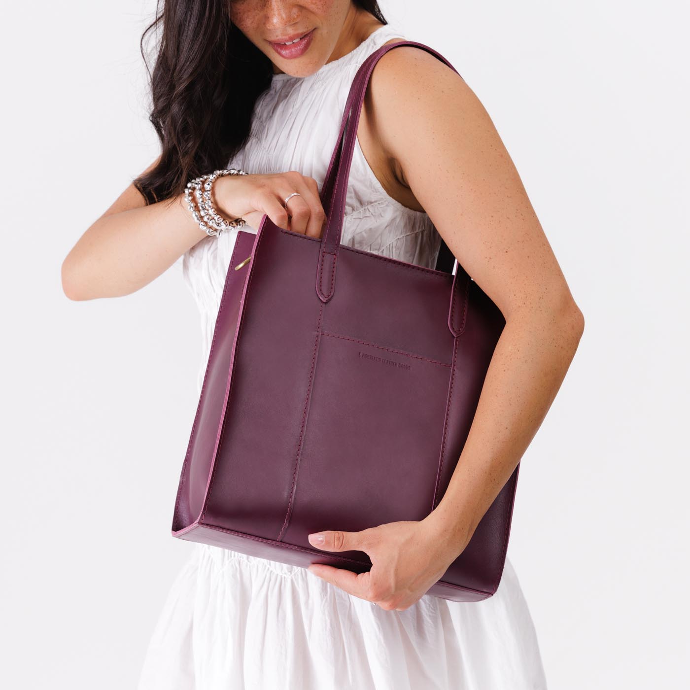 Lollipop*North/South | Model holding structured large tote bag with overlapping panels and crossbody strap