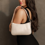 Bone | Model holding petite bean shaped shoulder bag with a zipper closure