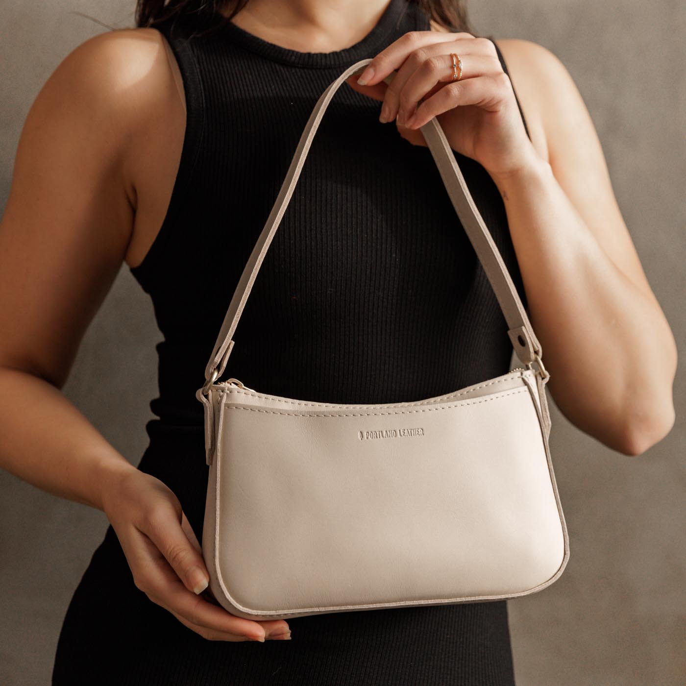 Bone | Model holding petite bean shaped shoulder bag with a zipper closure