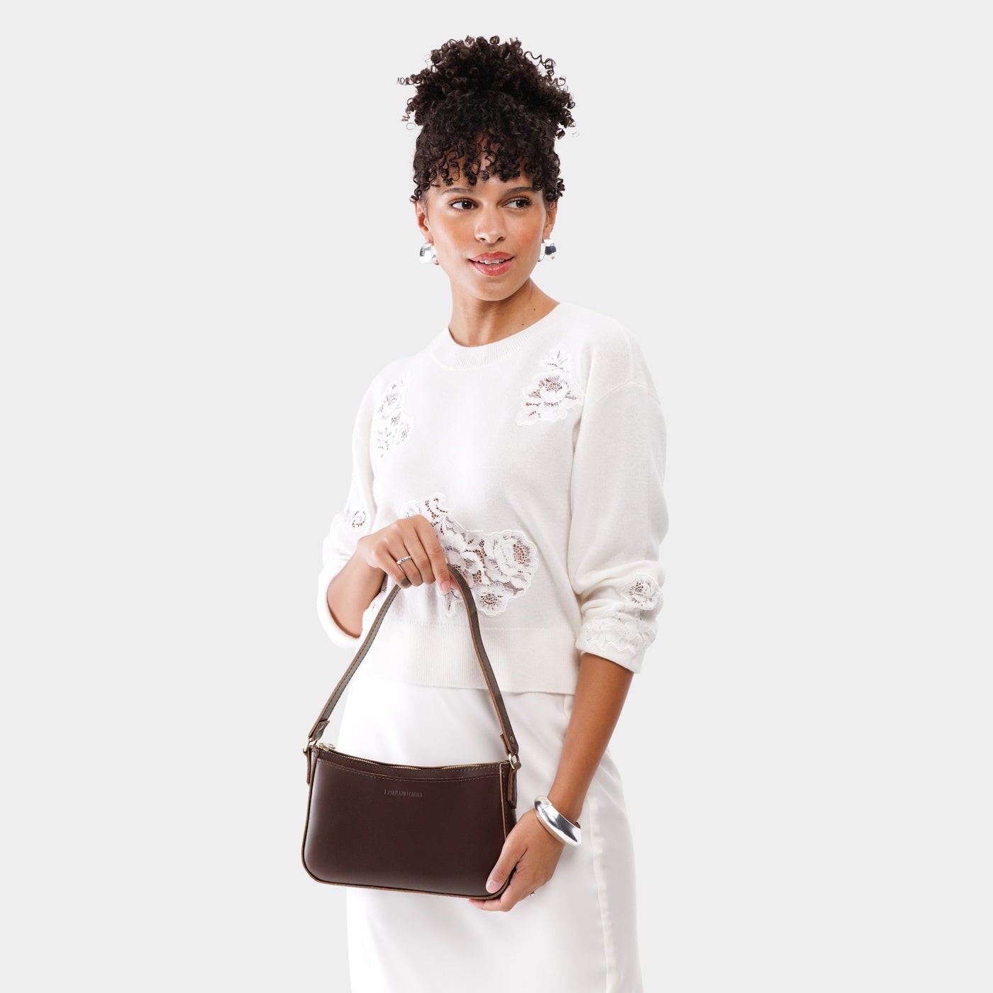 Chocolate Brown | Model holding petite bean shaped shoulder bag with a zipper closure