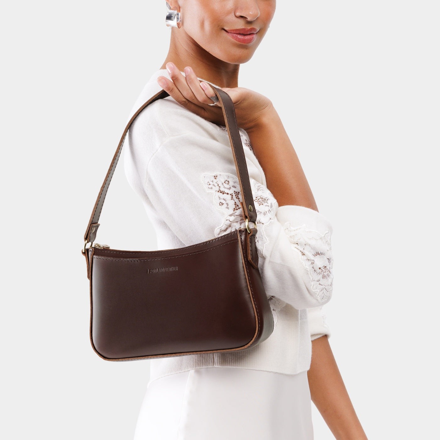 Chocolate Brown | Model holding petite bean shaped shoulder bag with a zipper closure