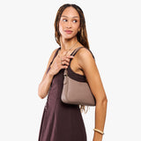 Sparrow Small | Model carrying petite bean shaped shoulder bag with a zipper closure