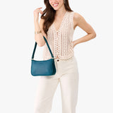 Westward Blue | Model carrying petite bean shaped shoulder bag with a zipper closure