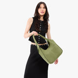 Laurel Large | A model holding a u-shaped, flat-bottomed leather shoulder bag with two outside pockets
