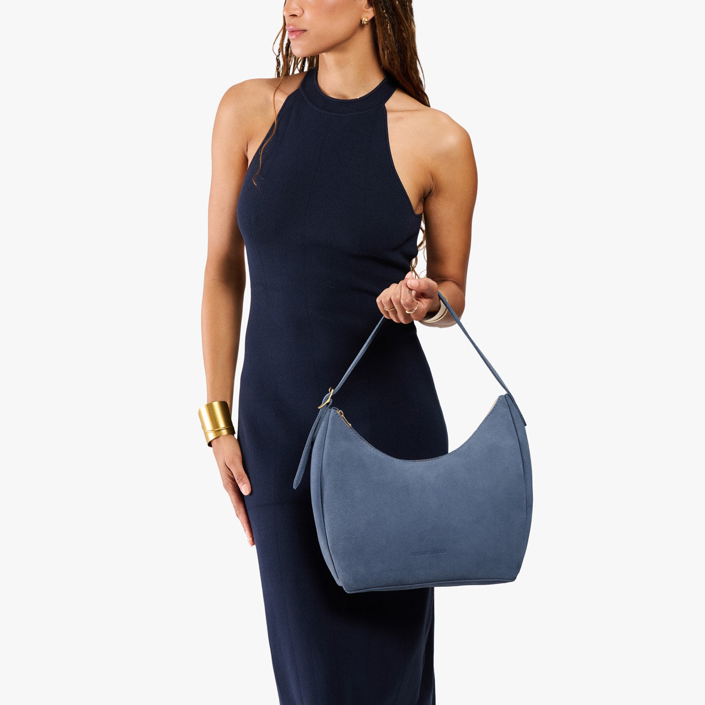 Denim*Medium | Model holding u-shaped, flat-bottomed leather shoulder bag with adjustable strap