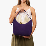 Imperial Medium | Model holding u-shaped, flat-bottomed leather shoulder bag with adjustable strap